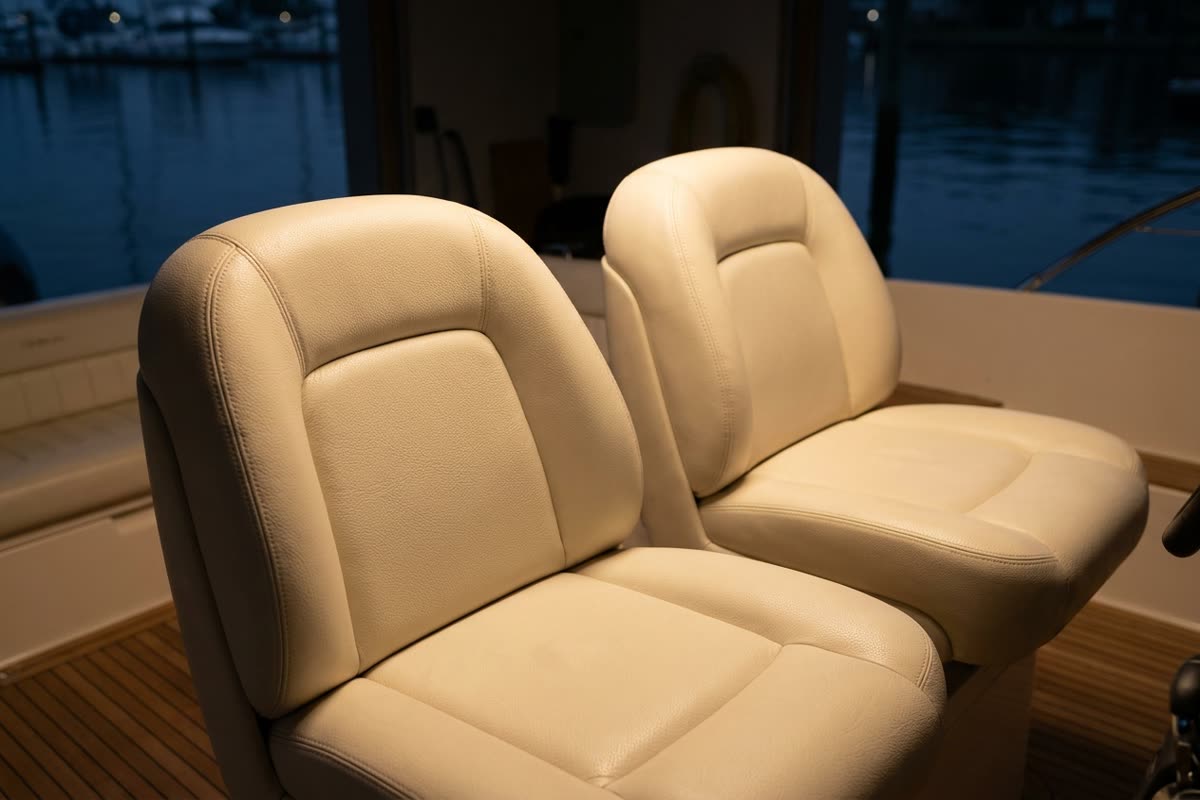 Cremefarbene Ledersitze im Cockpit einer Motoryacht mit Teakdeck